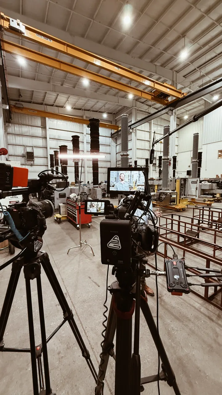 Camera and lighting crew filming inside an industrial facility