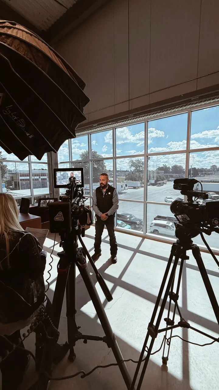 Camera and light stands set up beside a wall of windows for an interview
